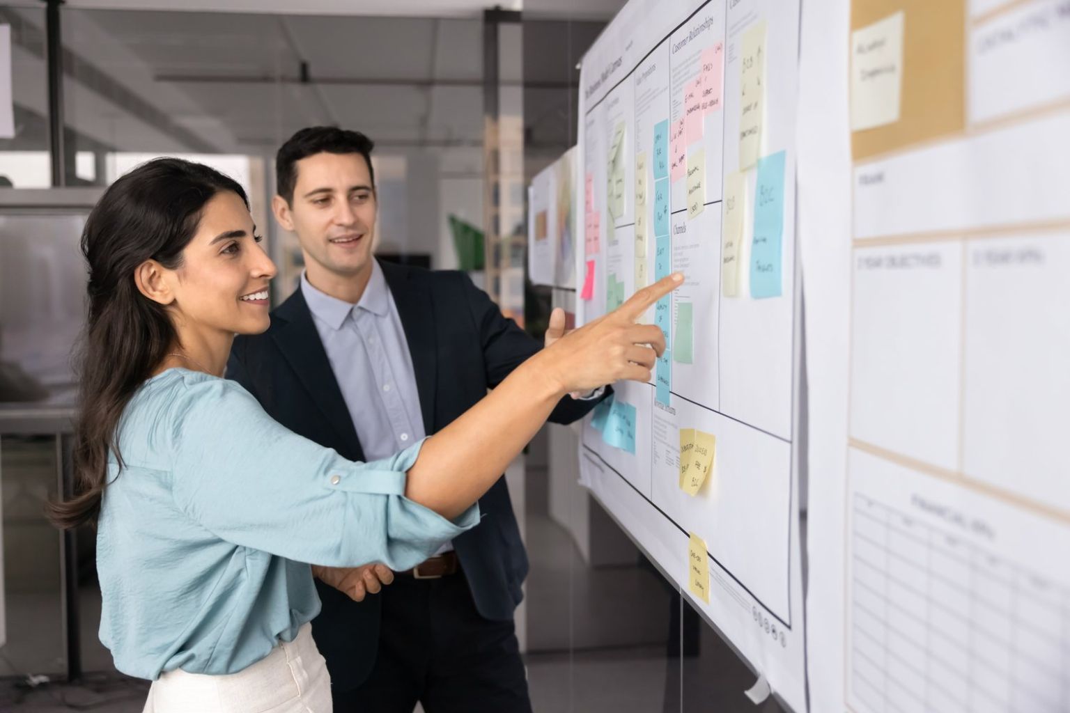 Two colleagues working through a business model canvas in a bright office — Stratdel fractional COO services in Houston